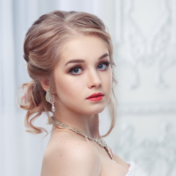 Woman with elegant hairstyle and makeup against a light background